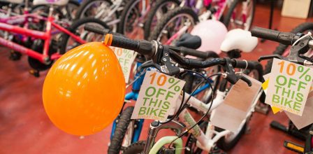 A bike with a "10% off this bike" sign attached to one handlebar and an orange balloon attached to the other