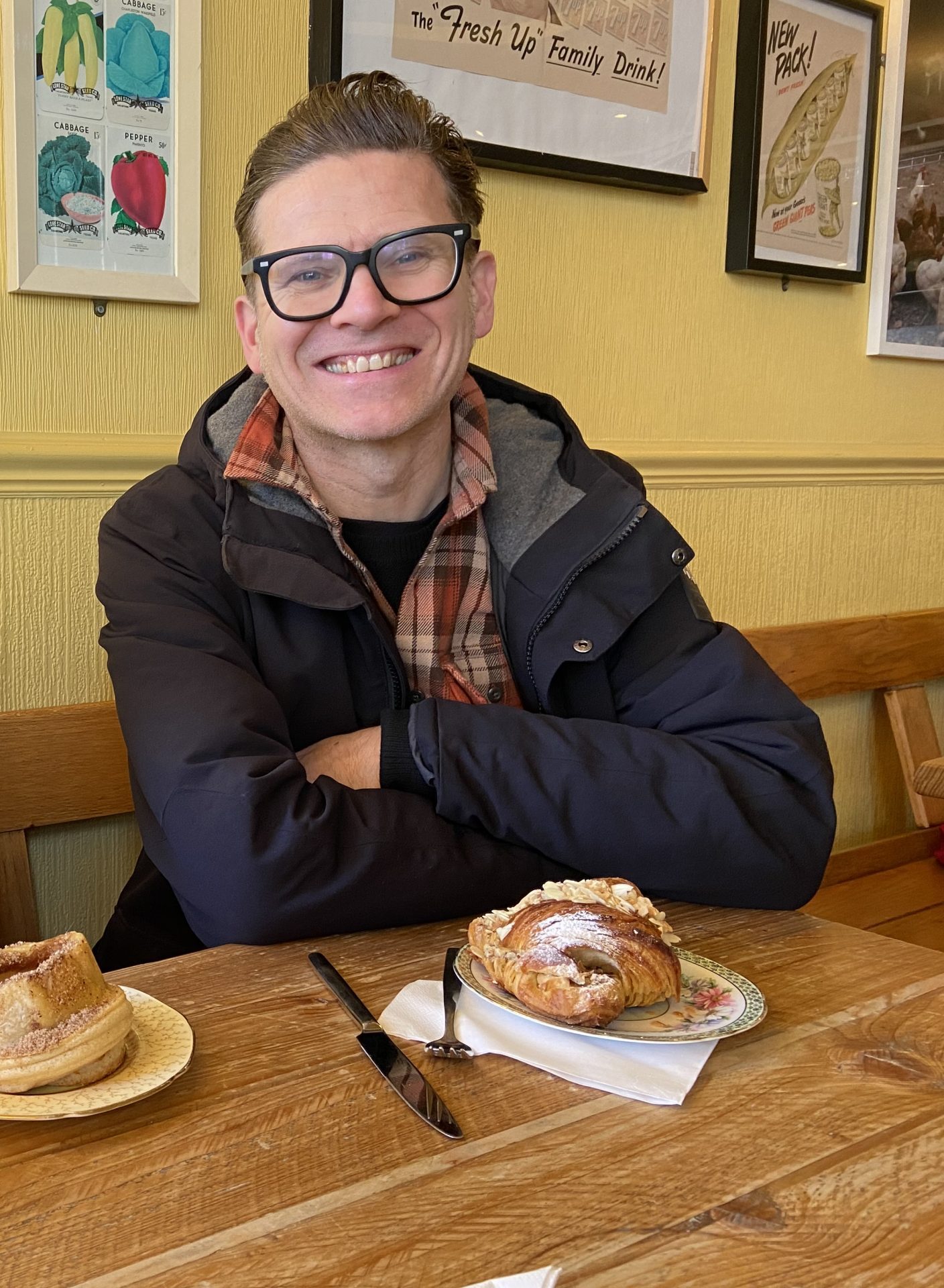 A man sitting at a table in a cafe with pastries